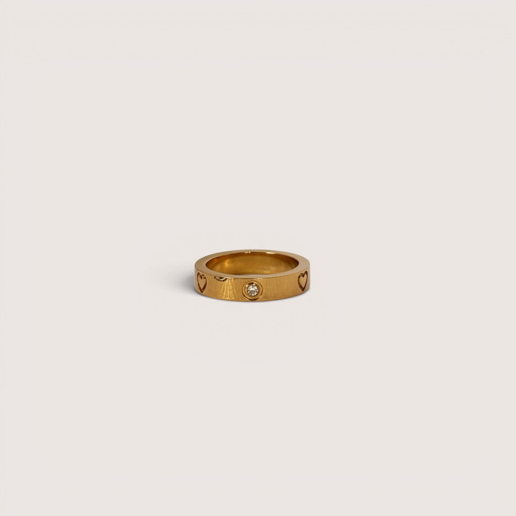 Anillo Magillas de acero inoxidable dorado con diseño de corazones y una pequeña circonita central.