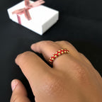 Anillo tejido ajustable de Magillas con cuentas doradas sobre cordón negro.