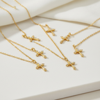 Collar Magillas con colgante de cruz en tono dorado con pequeñas piedras brillantes sobre fondo blanco