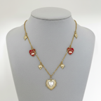 Collar Magillas dorado con dijes de corazones rojos, ojos turcos y un colgante central de corazón estilo sol.