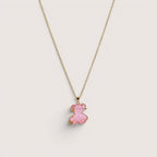Collar de Magillas con colgante de oso rosa translúcido y detalles dorados.