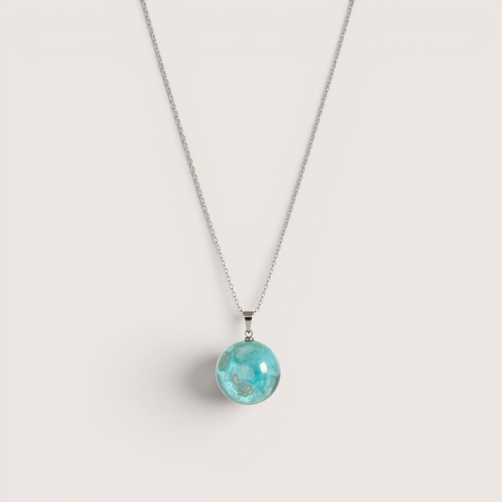 Collar Magillas de resina azul con colgante esférico que simula nubes.