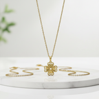 Collar Magillas con colgante de trébol de cuatro hojas en tono dorado sobre una base de mármol blanco