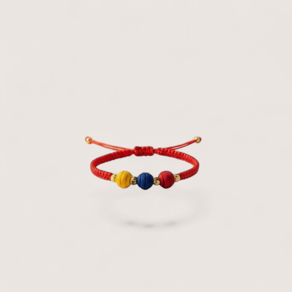 Magillas Colombian football fan bracelet with red, blue, and yellow beads and gold accents on a red cord.