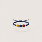 Magillas blue braided bracelet with red, blue, and yellow beads and gold accents. Adjustable.