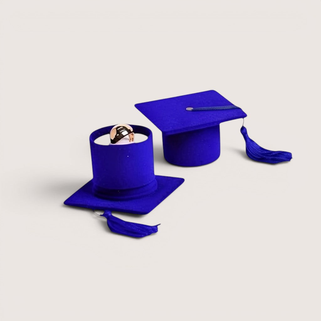 Estuche para anillos con forma de birrete de graduación azul de Magillas, con borla morada.