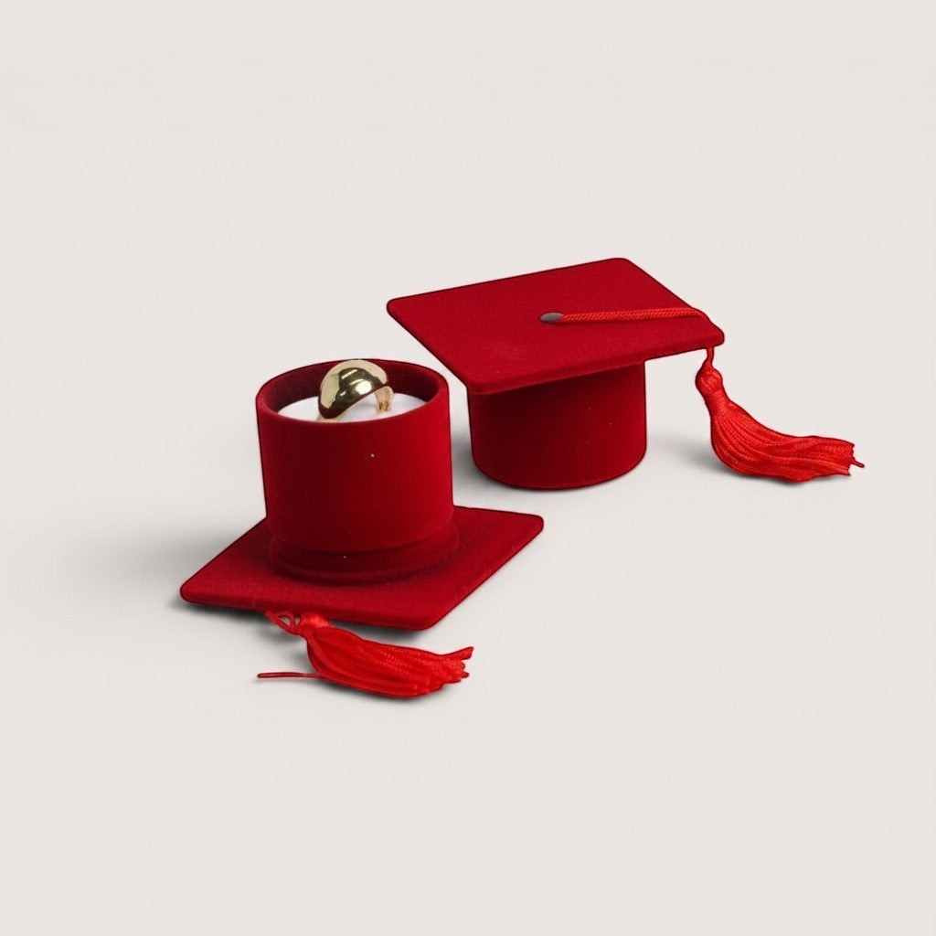 Magillas estuche de terciopelo rojo con forma de birrete de graduación, con borla roja y anillo dorado en el interior.