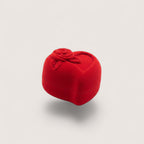 Magillas estuche de terciopelo rojo en forma de corazón con rosa en relieve, sostenido en una mano.