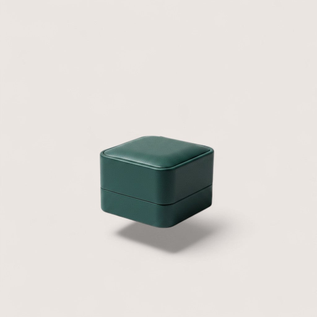 Estuche de joyería Magillas de cuero verde esmeralda, diseño cuadrado y compacto.