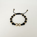 Magillas black beaded bracelet with gold infinity symbol and black rhinestones, made of stainless steel, rhodium, and neoprene.