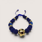 Pulsera Magillas con diseño de balón de fútbol en dorado, elaborada en acero inoxidable, neopreno y rodio, con cuentas azules.