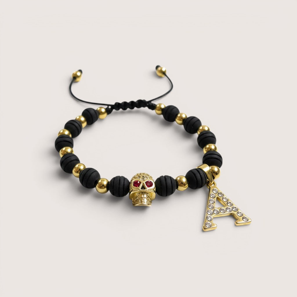 Pulsera Magillas de acero inoxidable, neopreno y rodio con letra A y calavera con ojos rojos.