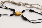 Pulsera de acero inoxidable Magillas con imán, disponible en negro y beige, con cuentas doradas y plateadas.